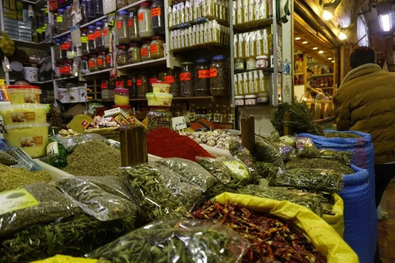 Un homme traverse un marché animé, entouré d'un assortiment d'épices aux couleurs vives et aux arômes alléchants.