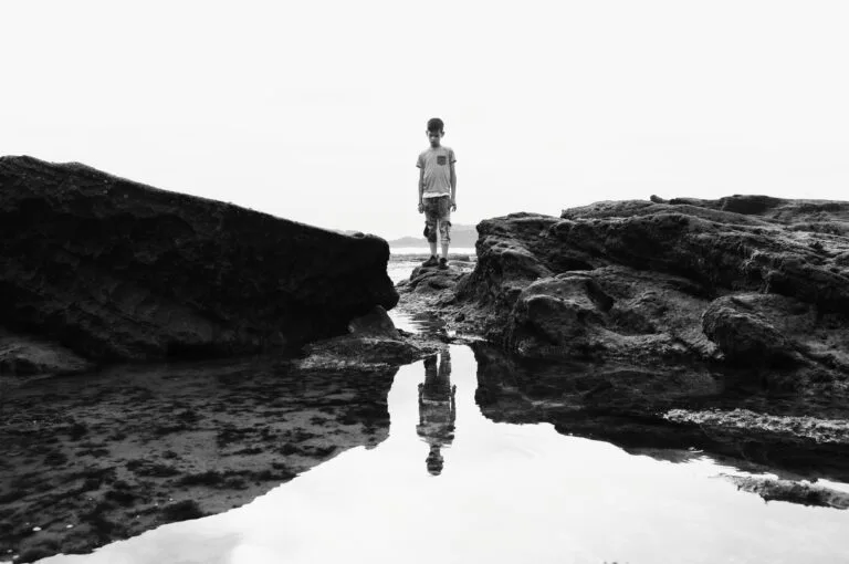 Un enfant debout sur la plage d'Essaouira et regardant l'eau