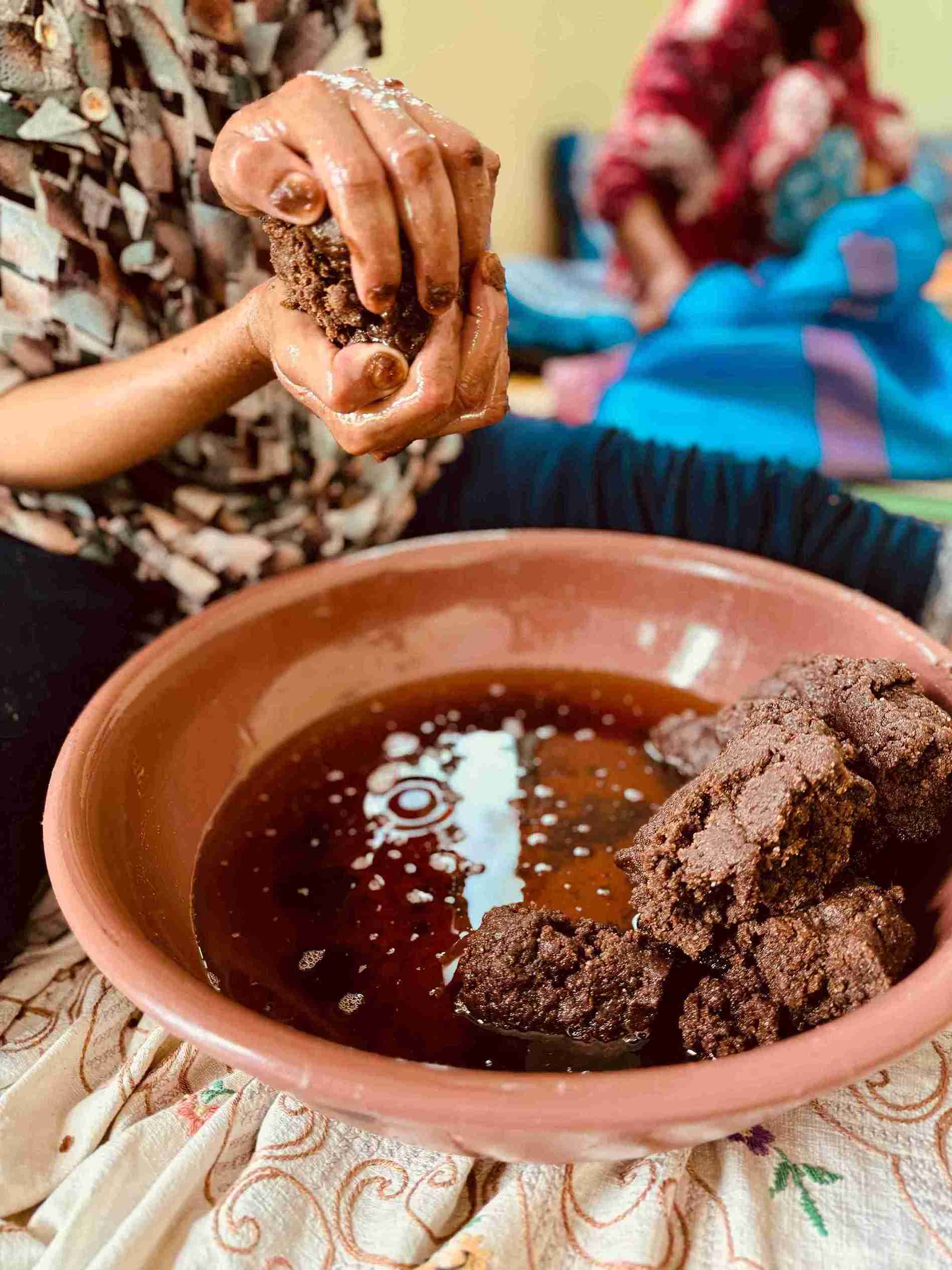 hands pressing argan to extract argan oil